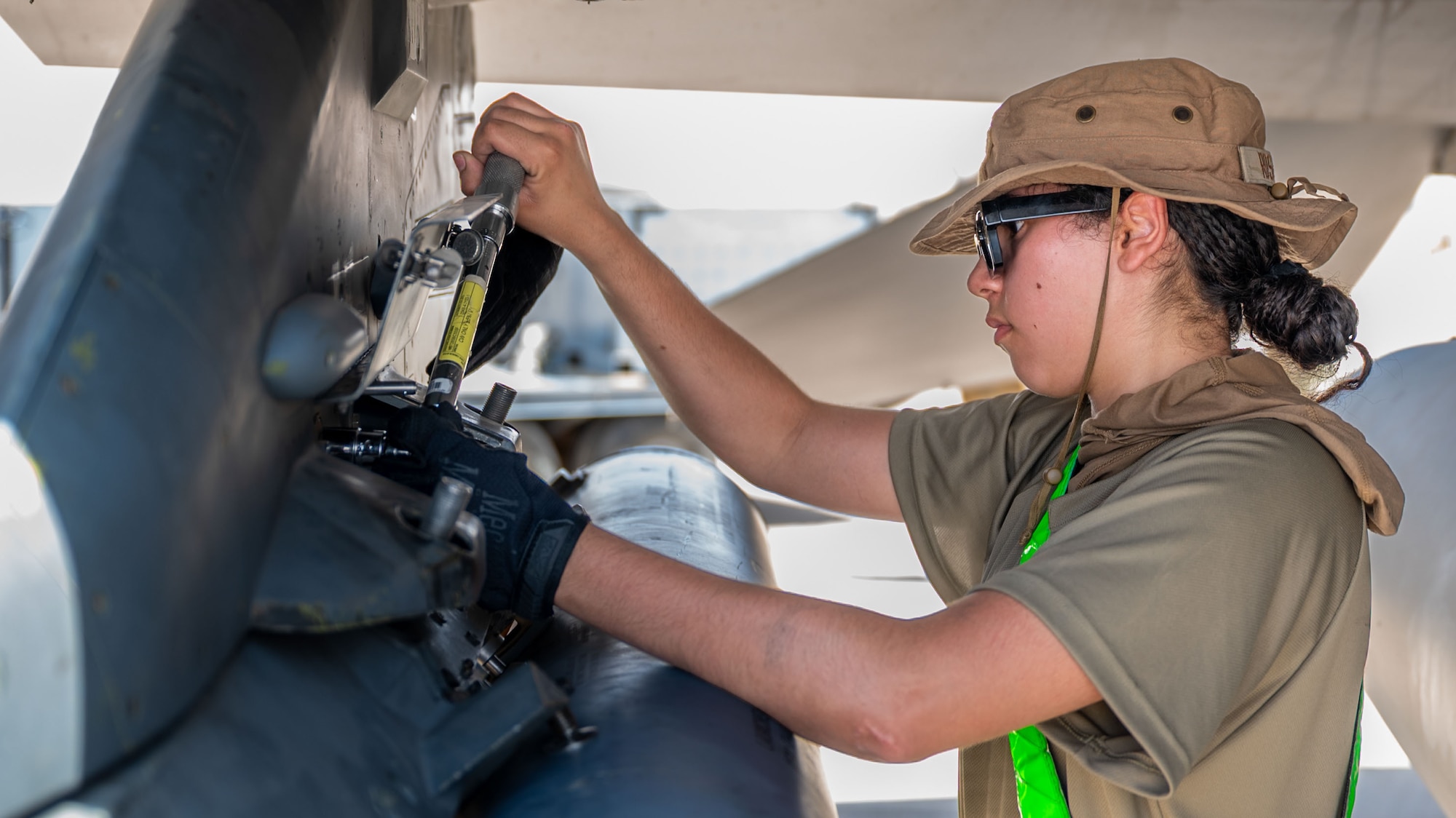 An Airman tightens a Triple Ejector Rack-9/A to an F-16 Fighting Falcon.