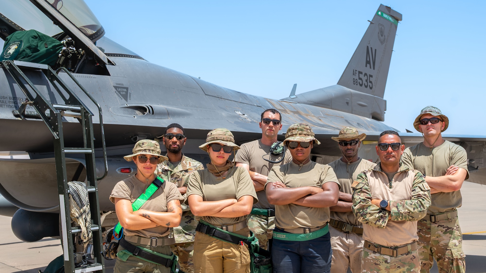 Airmen pose for a photo in front of an F-16 Fighting Falcon.