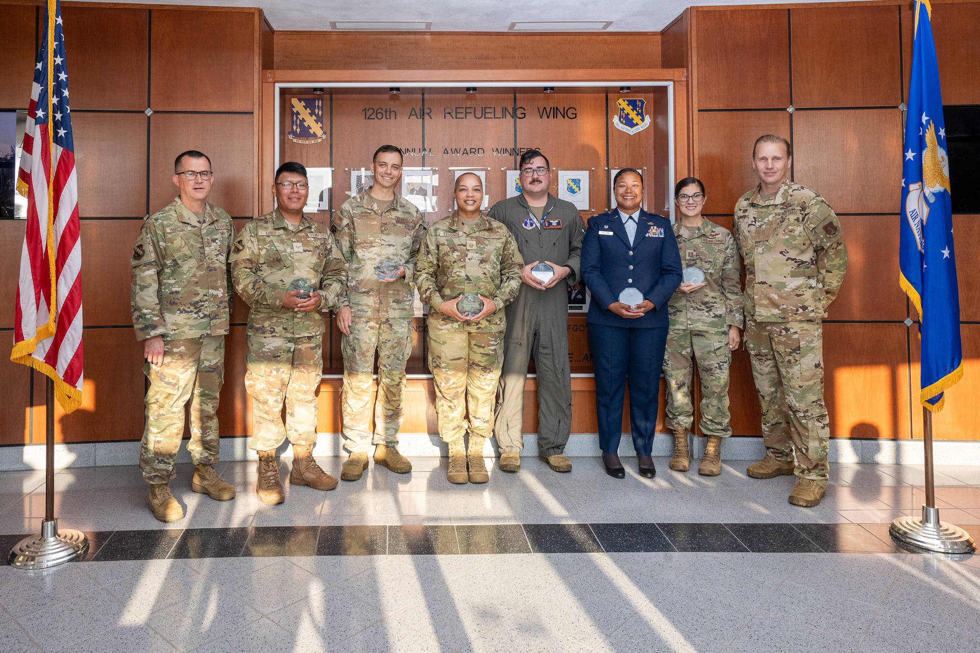 6 Airmen holding awards with the Wing commander to the right and Wing Command Chief Master Sgt. on the left