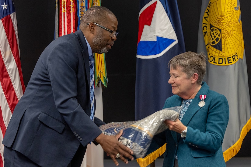Retired Command Sgt. Maj. Gennaro Penn, U.S. Army Finance Corps Association president, gives a token of appreciation to Susan Gillison, USAFMCOM Military Pay Operations director, during Gillison’s retirement ceremony at the Maj. Gen. Emmett J. Bean Federal Center in Indianapolis Oct. 28, 2024. Gillison, a Mercer, Pennsylvania native, is an Army veteran whose service to the nation spans 41 years with more than 2 years in the U.S. Army Reserve, more than 21 years in the Regular Army, and more than 17 years of government civilian service with the Defense Finance and Accounting Service and USAFMCOM. (U.S. Army photo by Mark R. W. Orders-Woempner)