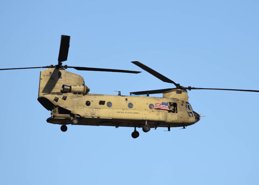 U.S. Army Sgt. Thriska Smith assigned to the Combat Aviation Brigade, 1st Armored Division displays an American flag to the crowd from a CH-47F Chinook helicopter during the 4th Annual Black Sea Air Show at Mihail Kogălniceanu International Airport, Romania, August 2, 2025. The air show displayed military aircraft, vehicles, and equipment from the United States, Romania, Italy, and Germany for exhibitors, visitors, and military delegations. This event provided an opportunity for Army aviation crews to demonstrate their elite flying skills and abilities while also demonstrating the U.S. commitment to providing forward deployed combat-credible forces in the region. (U.S. Army photo by Capt. Regina Koesters)