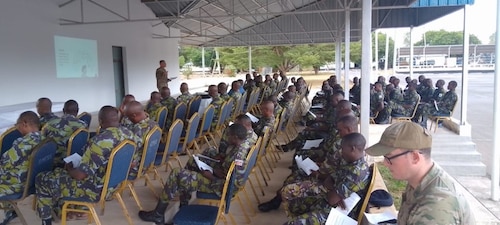 Men part of the Kenyan Defense Forces, sit and listen to a member of the Religious Support Team provide resiliency training.