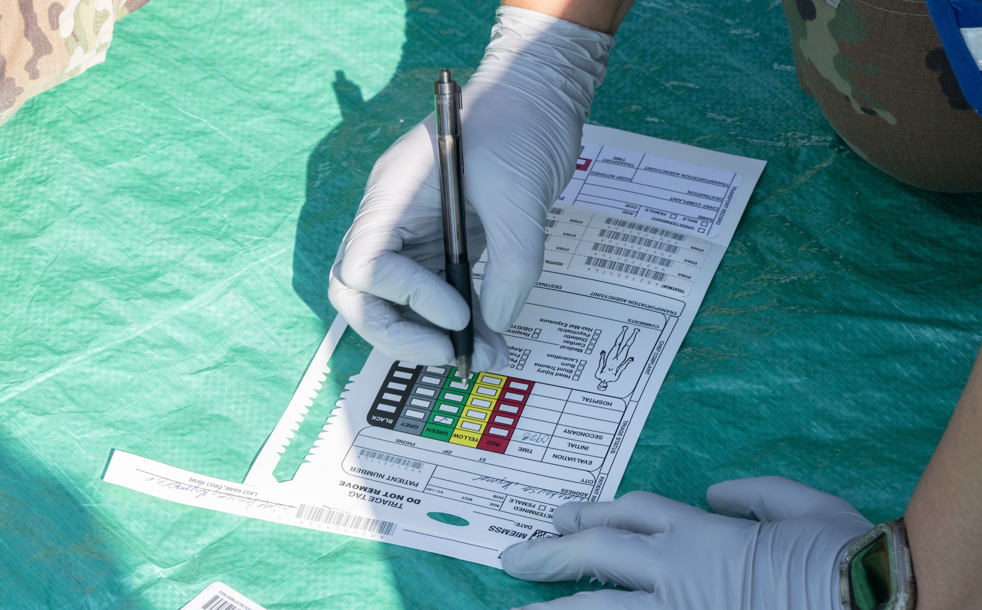 A U.S. Air Force member with the Andrews Medical Group field response team fills out a triage tag for a patient’s simulated injuries during a field training exercise at Joint Base Andrews, Md., July 24, 2025. The team rehearsed injury documentation and prioritization under emergency conditions.