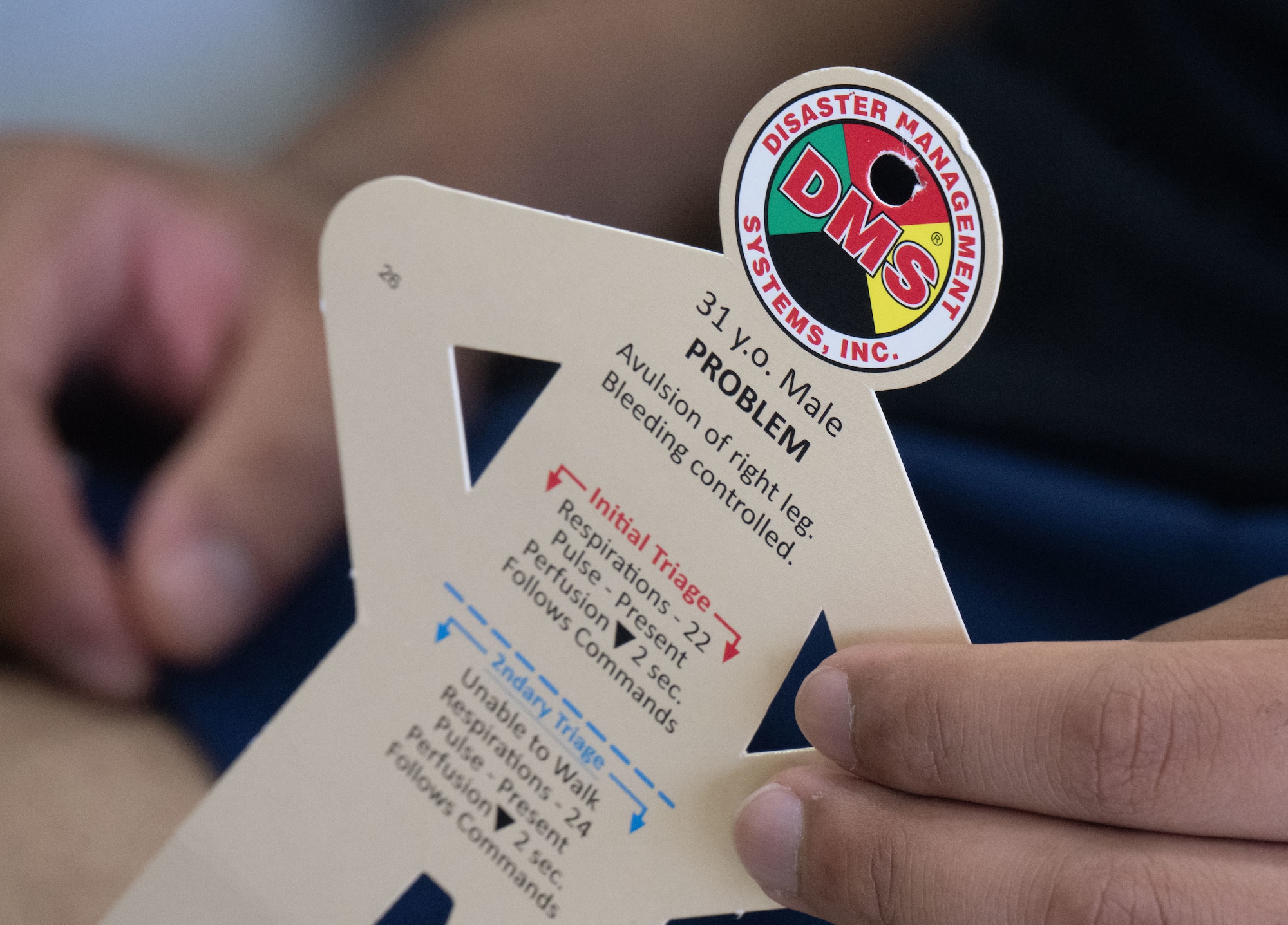 A participant acting as an injured patient holds an injury identification card during a field training exercise at Joint Base Andrews, Md., July 24, 2025. The card displays simulated medical conditions for the Andrews Medical Group field response team to assess and treat.