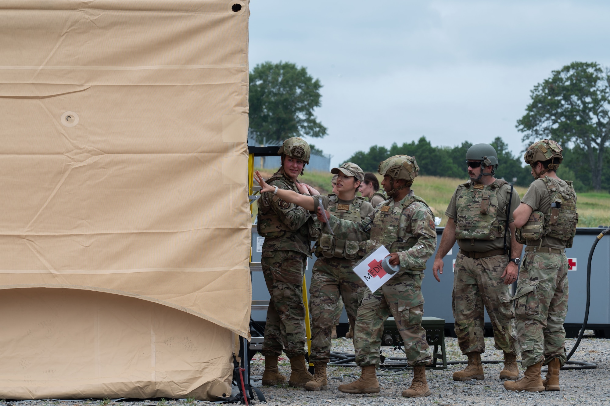 Airmen stand outside next to a tent
