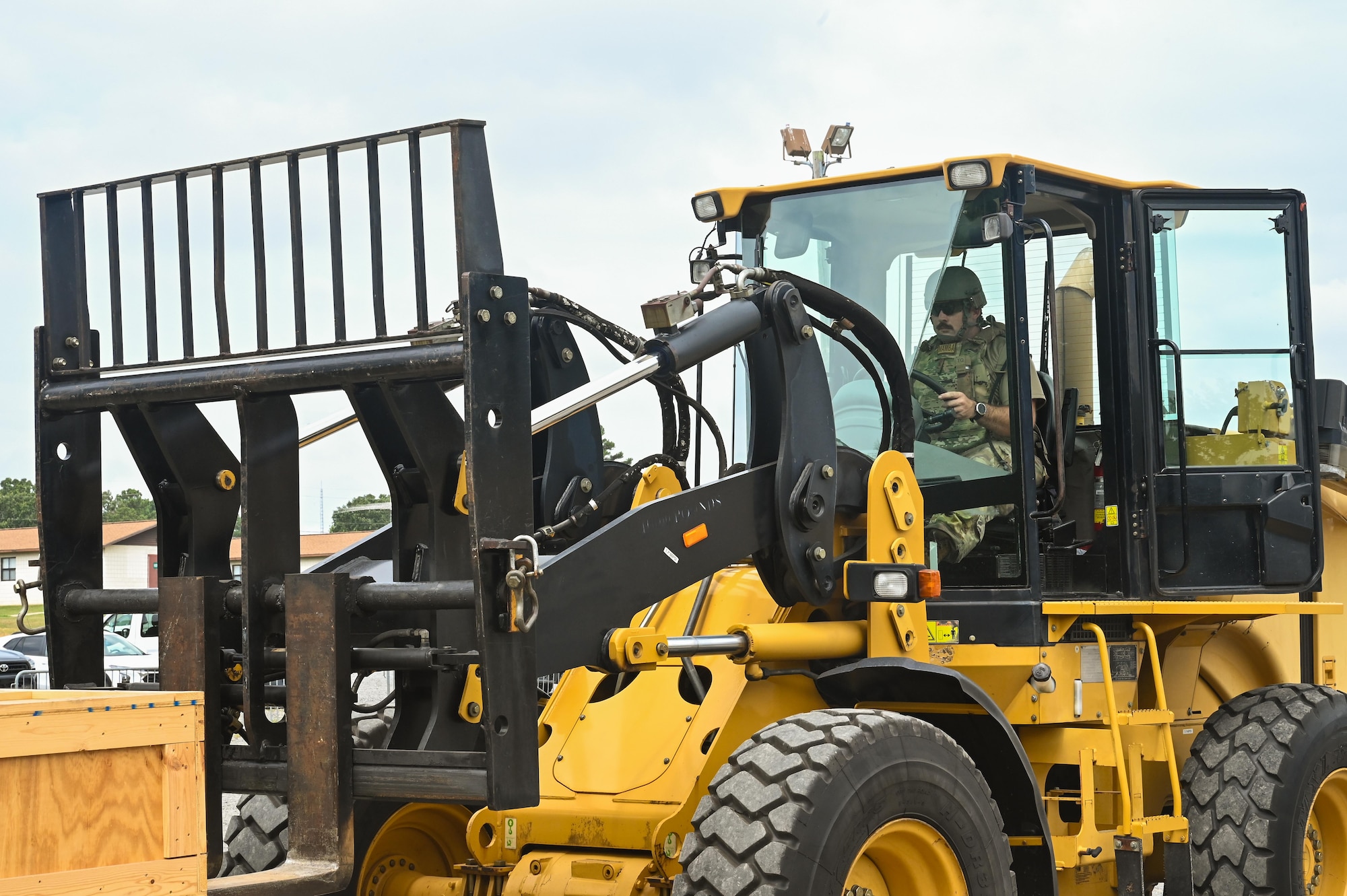 An Airman drives a large yellow forklift