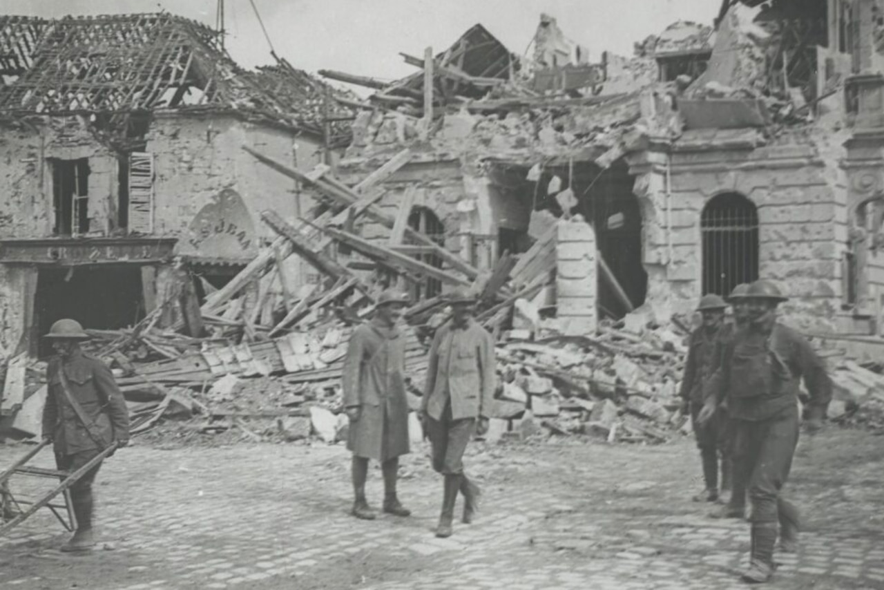 Soldiers walk around destroyed buildings.