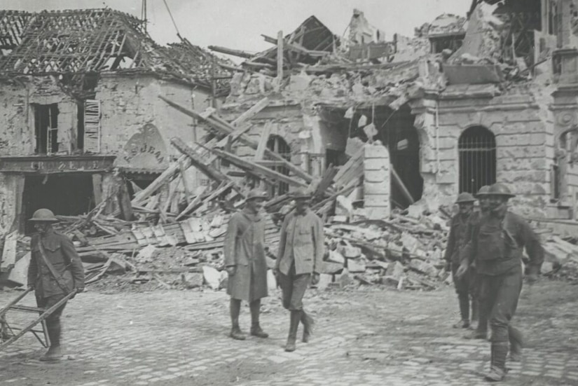 Soldiers walk around destroyed buildings.