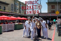 Sailors assigned to the guided missile destroyer USS Jack H. Lucas (DDG 125) and Marines with Headquarters and Service Battalion, 1st Marine Logistics Group, pose for a photo with U.S Navy Capt. Gervy Alota at Pike Place Market during Seattle Fleet Week, July 30, 2025. Seattle Fleet Week is a time-honored celebration of the sea services and provides an opportunity for the citizens of Washington to meet Sailors, Marines and Coast Guardsmen, as well as witness firsthand the latest capabilities of today’s maritime services. (U.S. Navy photo by Mass Communication Specialist 2nd Class Evan Diaz)