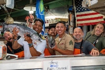 U.S Navy Capt. Gervy Alota and U.S. Marine Sgt. Carrasco Rodriguez with Headquarters and Service Battalion, 1st Marine Logistics Group, pose for a photo while holding fish at Pike Place Market during Seattle Fleet Week, July 30, 2025. Seattle Fleet Week is a time-honored celebration of the sea services and provides an opportunity for the citizens of Washington to meet Sailors, Marines and Coast Guardsmen, as well as witness firsthand the latest capabilities of today’s maritime services. (U.S. Navy photo by Mass Communication Specialist 2nd Class Evan Diaz)