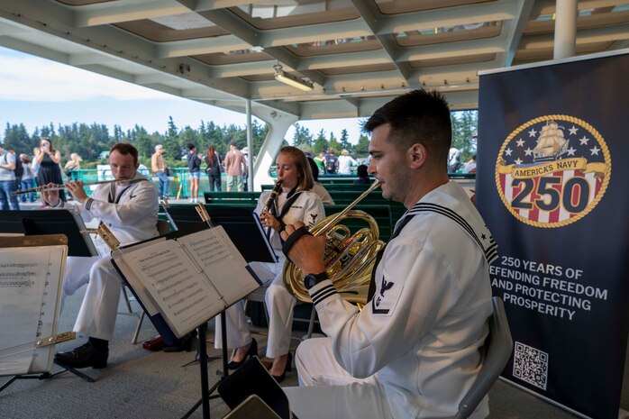 Musician 3rd Class Dean Bradly (left), from Naperville, Ill., plays a flute, Musician 2nd Class Hannah Thorp (middle), from Dallas, plays a clarinet, and Musician 3rd Class Scott Ullman (right), from Moorpark, Calif., plays a French horn while performing on the Seattle ferry during Seattle Fleet Week 2025. Seattle Fleet Week is a time-honored celebration of the sea services and provides an opportunity for the citizens of Washington to meet Sailors, Marines and Coast Guardsmen, as well as witness firsthand the latest capabilities. of today’s maritime services. (U.S. Navy photo by Mass Communication Specialist Seaman Joey Sitter)