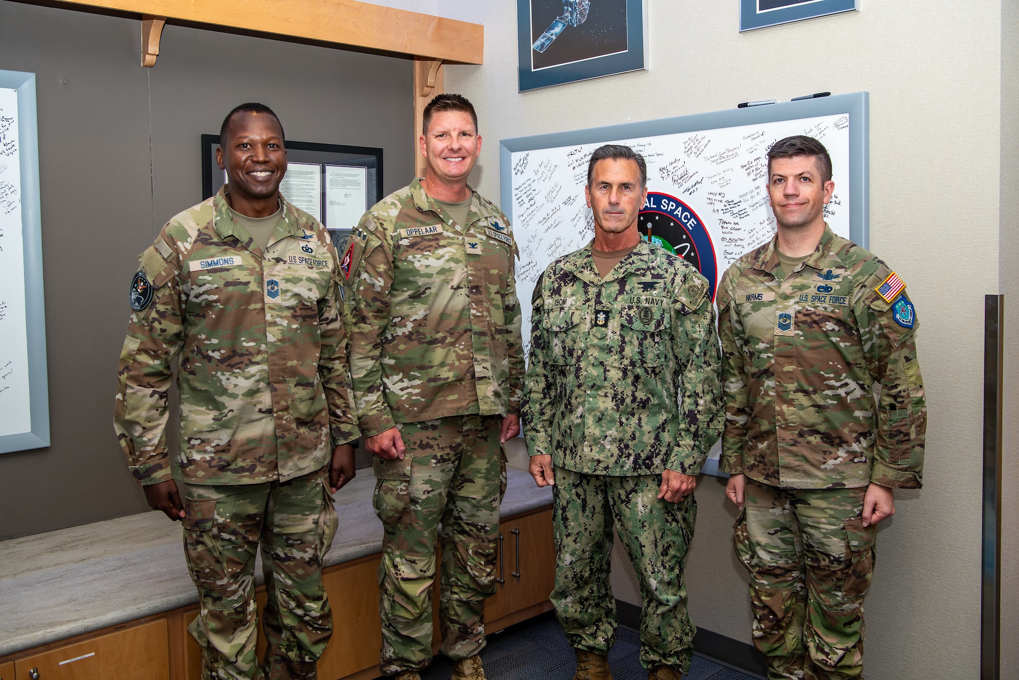 Four military members in uniform stand together for a photo.