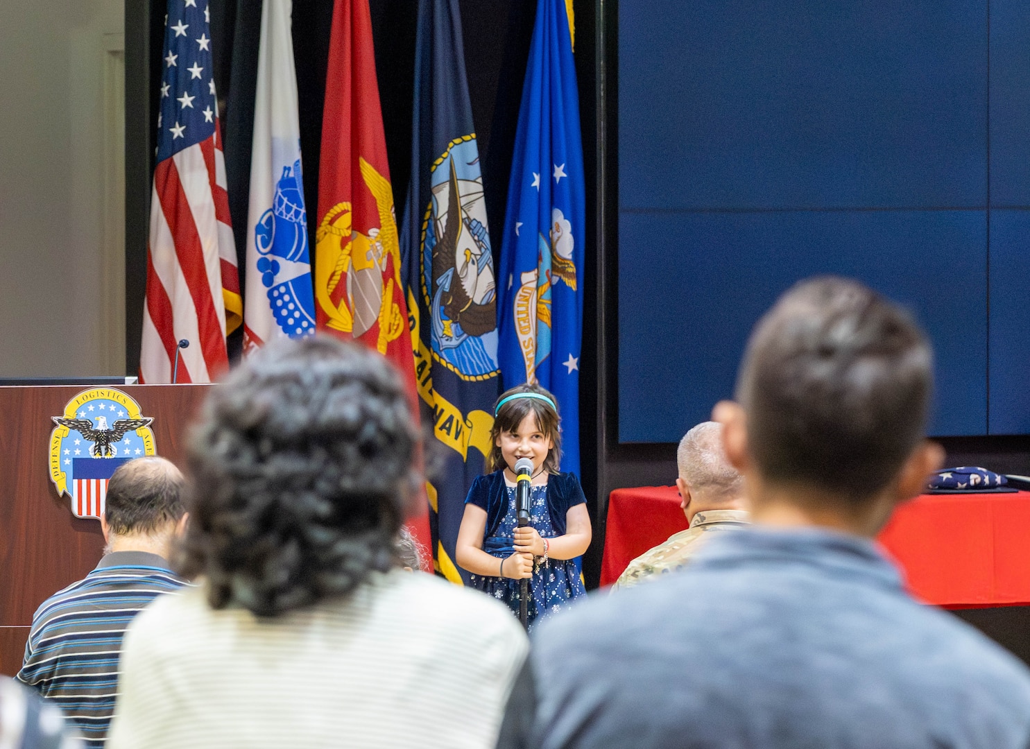 A girl stands on stage with a microphone.