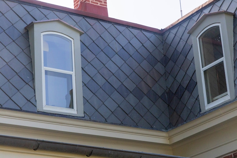 A close-up view of a grey slate roof with two windows.