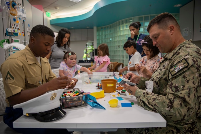 Boatswain’s Mate 1st Class Nathan Burnau (right), from Barstow, Calif., assigned to the Arleigh Burke-class guided missile destroyer USS Jack H. Lucas (DDG 125), and Lance Cpl. Austin Miller (left), from Southaven, Miss., assigned to amphibious transport dock ship USS Somerset (LPD 25), play with Legos with patients at the Seattle Children’s Hospital during Seattle Fleet Week 2025. Seattle Fleet Week is a time-honored celebration of the sea services and provides an opportunity for the citizens of Washington to meet Sailors, Marines and Coast Guardsmen, as well as witness firsthand the latest capabilities. of today’s maritime services. (U.S. Navy photo by Mass Communication Specialist Seaman Joey Sitter)