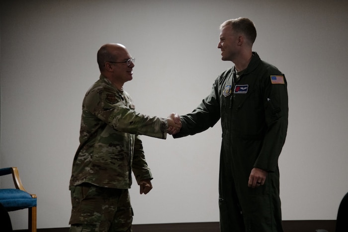 An Airmen coins another Airmen in a flight suit.