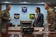 U.S. Air Force Col. Jesse Lamarand, 5th Bomb Wing commander (left), and U.S. Air Force Col. James Schlabach, 91st Missile Wing commander (right), provide a welcome brief to Robert Karem, congressional staff delegate (center), at Minot Air Force Base, Aug. 5, 2025. The brief covered information about Minot AFB and its vital mission of deterrence.
