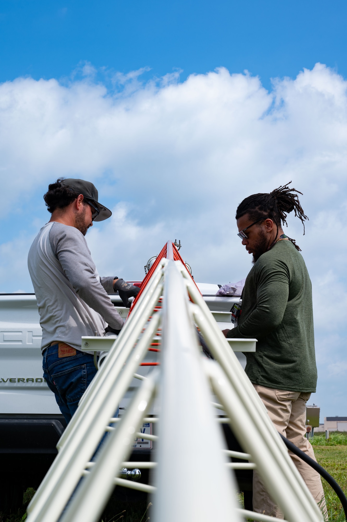 Jorge Caceres, Naval Information Warfare Center mechanical engineer and Jonathan White, Trandes Corporation engineering technician V, set up a Moving Target Indication Reflector as part of the newly installed AN/FPN-68 Precision Approach Radar system at Joint Base McGuire-Dix-Lakehurst, N.J., July 17, 2025. The MTI Reflectors send a signal to the PAR system, which gets sent to the Bell UH-1Y and Bell AH-1Z--used by U.S. Marine’s assigned to Marine Aircraft Group 49--to indicate where they can safely land. (U.S. Air Force photo by Airman Haeleigh Bayle)