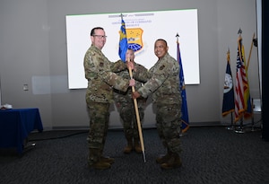 Col. Douglas C. Jeffrey IV, 433rd Airlift Wing commander, passes the 433rd Maintenance Group guidon to Col. Michael H. M. Egbalic, incoming 433rd Maintenance Group commander, during an assumption of command ceremony at Joint Base San Antonio-Lackland, Texas, Aug. 2, 2025.