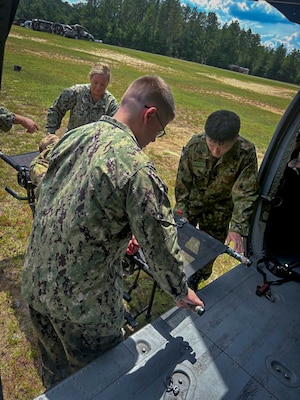 250729-N-N1574-1001 FORT RUCKER, Ala. (July 29, 2025) U.S. Navy and Japanese servicemembers carry a simulated casualty during the Joint Enroute Care Course (JECC) on Fort Rucker, Alabama, July 29, 2025. The purpose of JECC training is to operationalize clinical skills of servicemembers and introduce them to a standardized methodology for providing critical care while transporting a patient through the battle space during deployment as members of teams operating in austere environments. The course enhances joint interoperability by bringing together personnel from across the services to operationalize clinical skills and strengthen integrated medical response during deployment. (U.S. Navy photo by Lieutenant Commander Chelsea Godfrey)