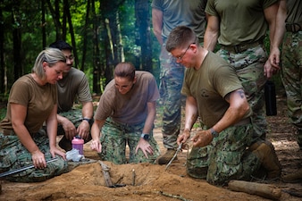250731-N-KC192-1005 FORT RUCKER, Ala. (July 31, 2025) Sailors assigned to Expeditionary Medicine teams work together to create a survival fire pit during Joint Enroute Care Course (JECC) survival training on Fort Rucker, Alabama, July 31, 2025. The purpose of JECC training is to operationalize clinical skills of servicemembers and introduce them to a standardized methodology for providing critical care while transporting a patient through the battle space during deployment as members of teams operating in austere environments. The course enhances joint interoperability by bringing together personnel from across the services to operationalize clinical skills and strengthen integrated medical response during deployment. (U.S. Navy photo by Mass Communication Specialist 2nd Class Levi Decker)