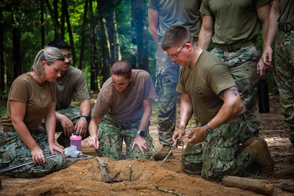 250731-N-KC192-1005 FORT RUCKER, Ala. (July 31, 2025) Sailors assigned to Expeditionary Medicine teams work together to create a survival fire pit during Joint Enroute Care Course (JECC) survival training on Fort Rucker, Alabama, July 31, 2025. The purpose of JECC training is to operationalize clinical skills of servicemembers and introduce them to a standardized methodology for providing critical care while transporting a patient through the battle space during deployment as members of teams operating in austere environments. The course enhances joint interoperability by bringing together personnel from across the services to operationalize clinical skills and strengthen integrated medical response during deployment. (U.S. Navy photo by Mass Communication Specialist 2nd Class Levi Decker)