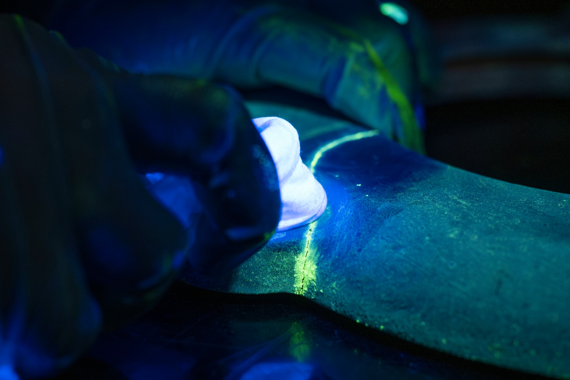 U.S. Air Force Staff Sgt. Estella Gilbert, 35th Maintenance Squadron Nondestructive Inspection (NDI) supervisor, inspects a mechanical component under black light at Misawa Air Base, Japan, Aug. 4, 2025.