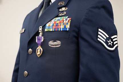 A closeup of an airman's uniform is shown with a Purple Heart medal.