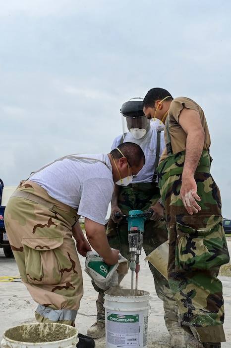 U.S. Air Force Staff Sgt. Luis Romano (left), 8th Civil Engineer Squadron heating, ventilation and air conditioning  spall team member, U.S. Air Force Senior Airman Nasir Harding (middle), 8th CES HVAC spall team member, and U.S. Air Force Senior Airman Gabriel Vivas (right), 8th CES HVAC spall team member, mix quick concrete together to patch holes during exercise Beverly Sentinel 25-3 at Kunsan Air Base, Republic of Korea, Aug. 6, 2025. To practice Rapid Airfield Damage Repair (RA/DR), the Red Devils practiced patching holes on the flightline where they were required to cut out and level damaged spots, clean up concrete debris, mix and pour concrete.
