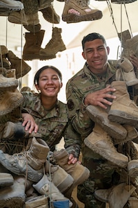 The Newmark twins poke their heads out of hanging boots through an opening mid-frame smiling for a photo