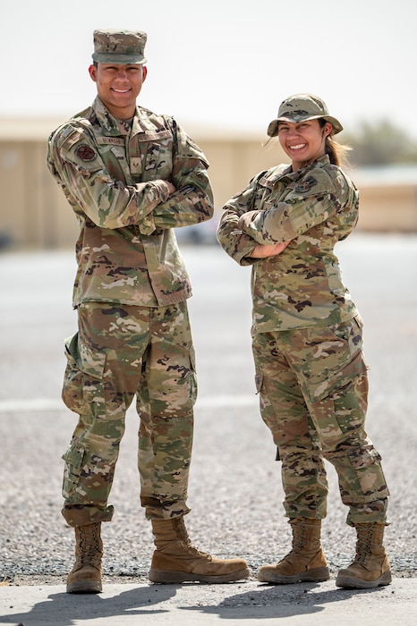 The Newmark twins stand side by side, facing inward with arms crossed