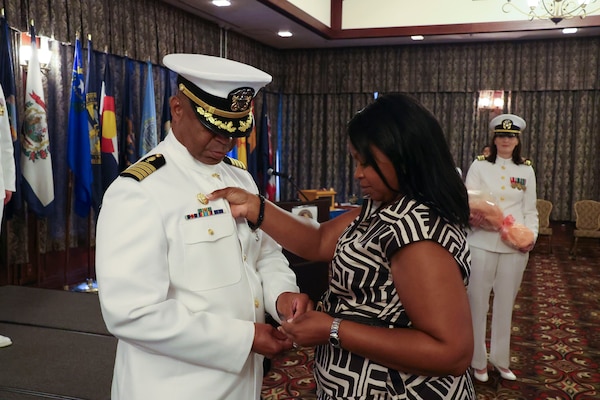 250601-N-DO281-2638 OKINAWA, Japan (Aug. 1, 2025) Capt. Gilliard's wife Tiffany places the command pin for Capt. Gilliard after taking command.  (U.S. Navy photo by Mass Communication Specialist 1st Class Trey Fowler)