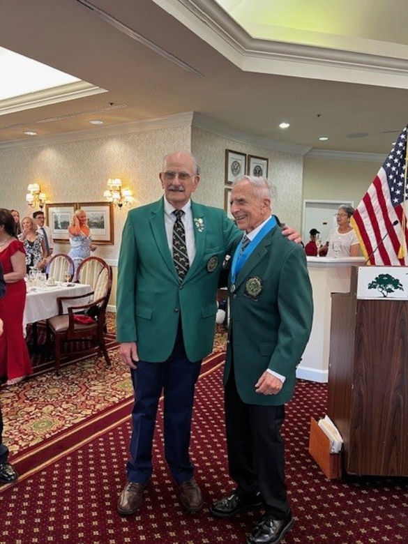 Two Army veterans stand next to each other, posing for a photo at a party.