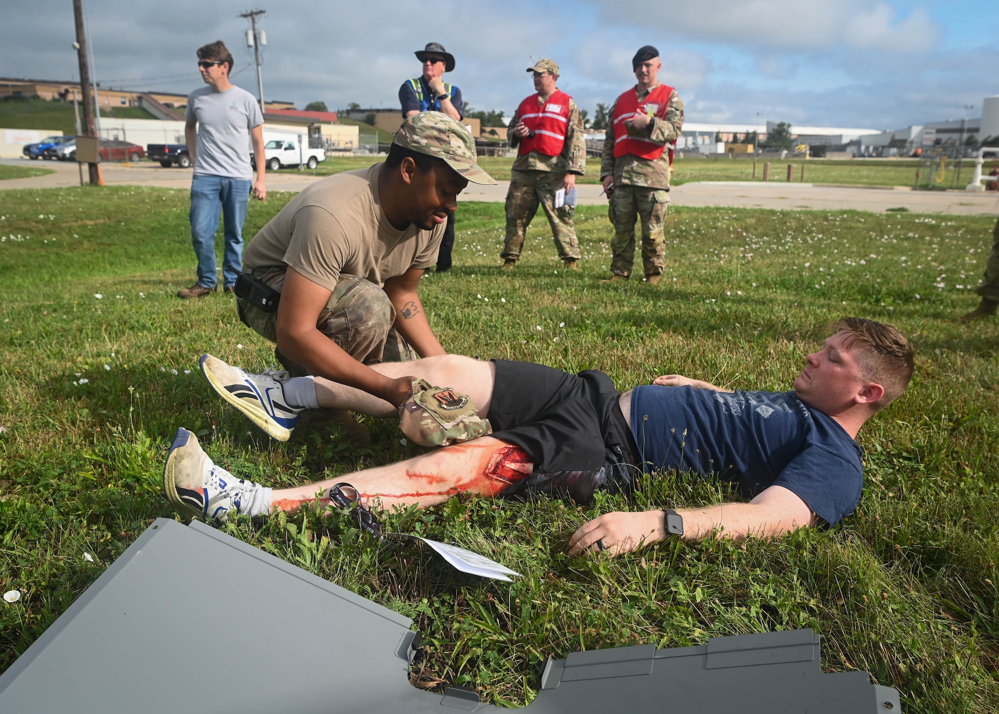 Senior Airman Jermaine Bartlett, 55th Logistics Readiness Squadron fuels facility technician, provides medical attention to Airman 1st Class Cameron McGurk, 55th LRS liquid fuels distribution operator, for a simulated leg injury during a Major Accident Response Exercise at Offutt Air Force Base, Nebraska, July 30, 2025. Members of the inspector general team stood by to watch and evaluate Bartlett’s response to the victim. (U.S. Air Force photo by Daniel Martinez)