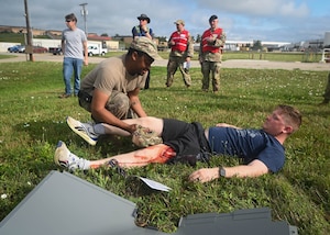 Senior Airman Jermaine Bartlett, 55th Logistics Readiness Squadron fuels facility technician, provides medical attention to Airman 1st Class Cameron McGurk, 55th LRS liquid fuels distribution operator, for a simulated leg injury during a Major Accident Response Exercise at Offutt Air Force Base, Nebraska, July 30, 2025. Members of the inspector general team stood by to watch and evaluate Bartlett’s response to the victim. (U.S. Air Force photo by Daniel Martinez)