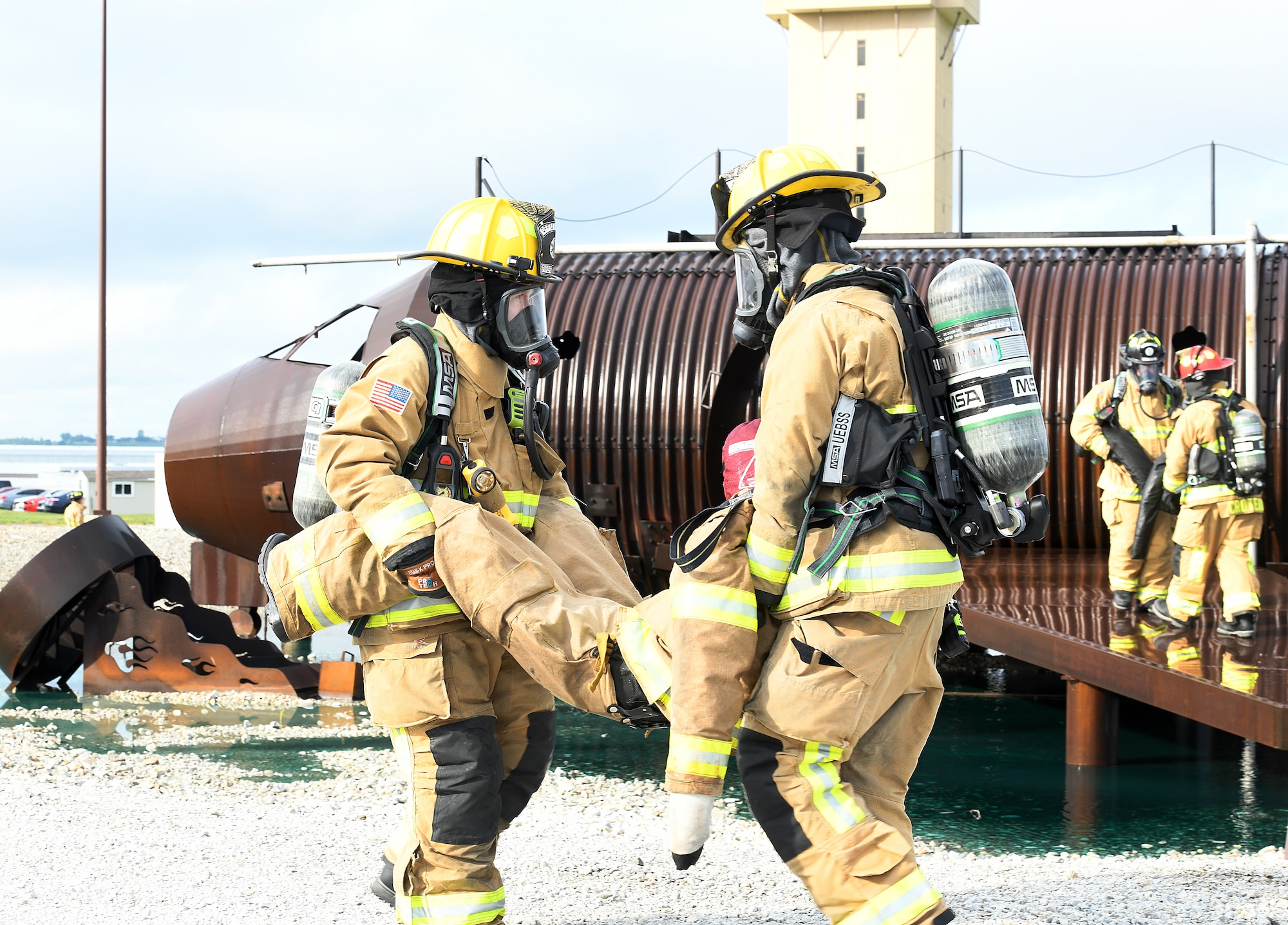 Offutt firefighters carry a dummy representing the pilot of a simulated downed aircraft on the Offutt Air Force Base flightline during a Major Accident Response Exercise at Offutt Air Force Base, Nebraska, July 30, 2025. Firefighters were on scene to subdue the blaze caused by the crashed aircraft and to tend to victims. (U.S. Air Force photo by Charles Haymond)