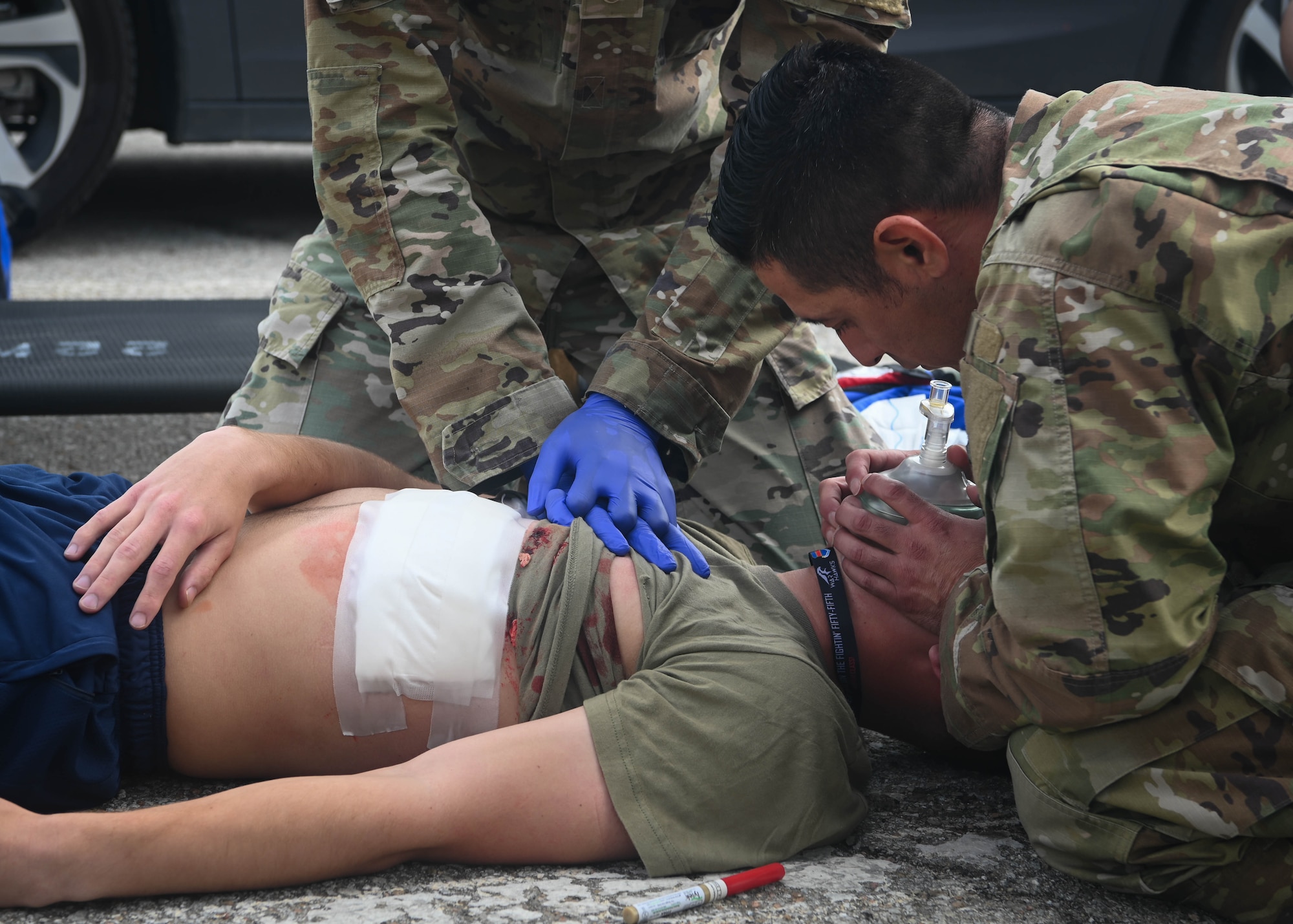 A 55th Medical Group Airman performs chest compressions while another 55th MDG Airman uses a CPR mask to provide oxygen to a simulated injured Airman during a Major Accident Response Exercise on Offutt Air Force Base, Nebraska, July 30, 2025. Emergency crews responded on scene to assist in the recovery and treatment of victims. (U.S. Air Force photo by Daniel Martinez)