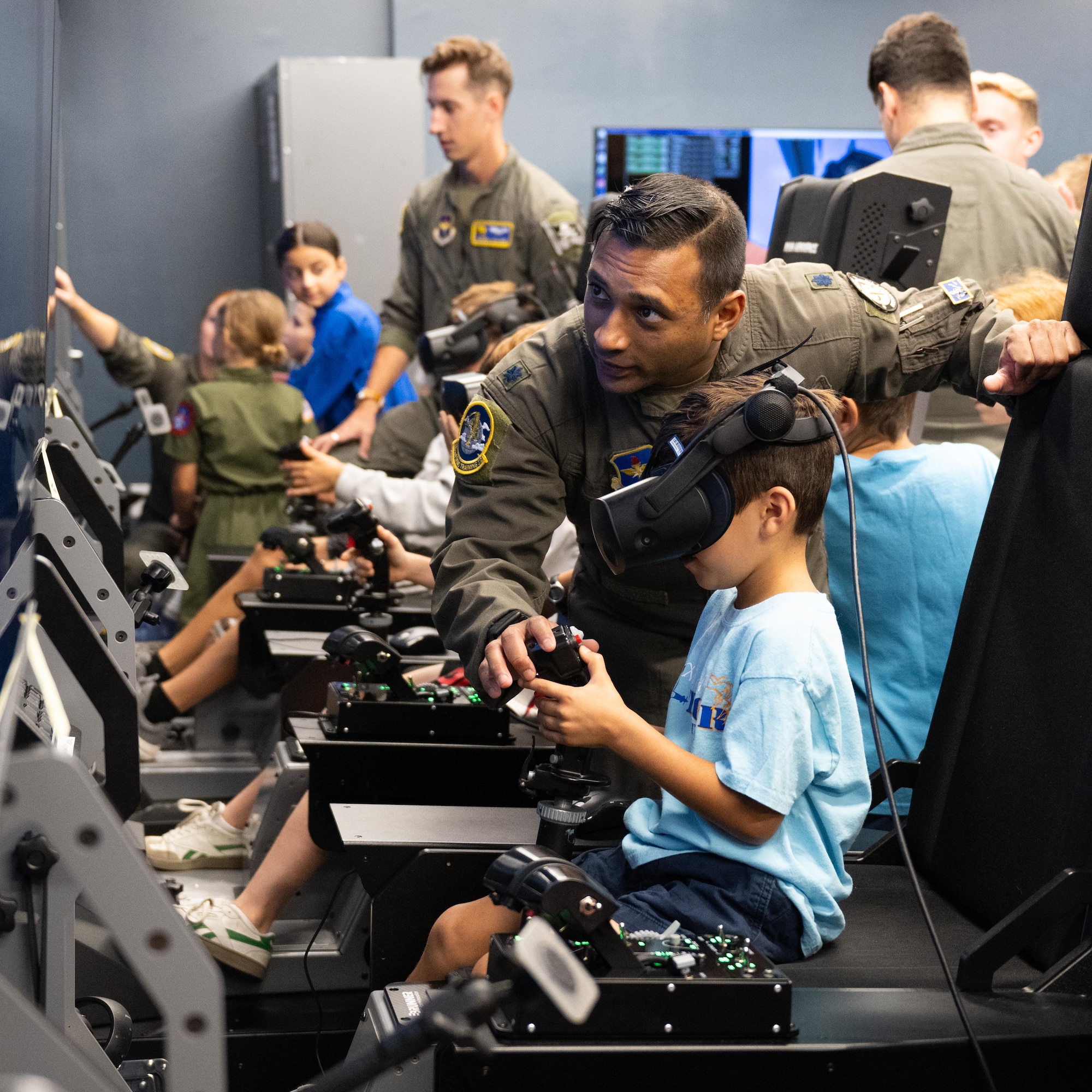 U.S. Air Force Lt. Col. Imran Khan, 85th FTS, commander assists a participant of Tiger for a Day with the controls in a flight simulator event at Laughlin Air Force Base, Texas, Aug. 5, 2025. Participants experienced flying a simulated T-6A Texan II with real-time instruction and guidance from experienced aviators. (U.S. Air Force photo by Airman 1st Class Harrison Sullivan)