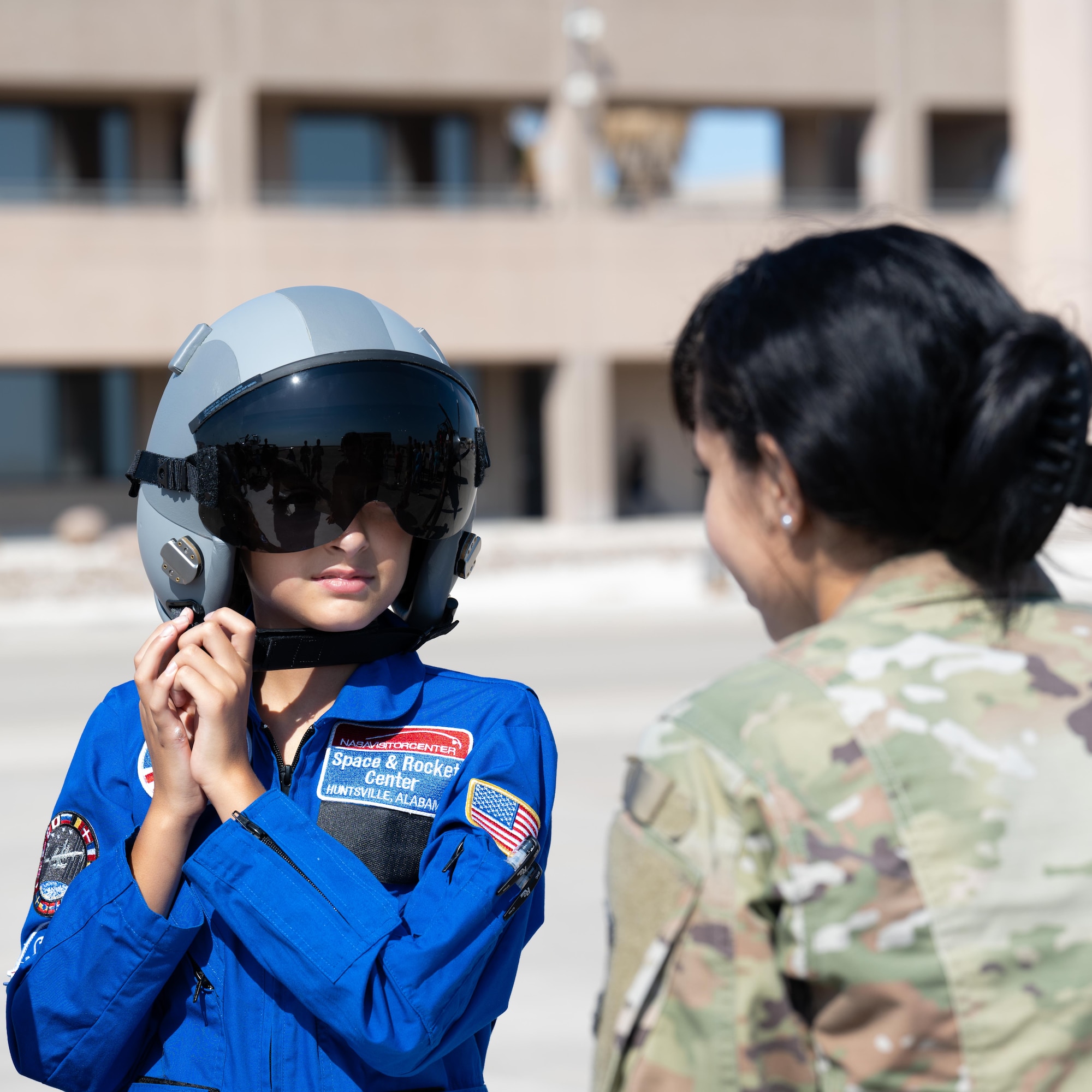 U.S. Air Force Airman 1st Class Andrea Lopez, 47th Operational Support Squadron, aircrew flight equipment technician, has a participant of the Tiger for a Day event try on the helmet that pilots use at Laughlin Air Force Base, Texas, Aug. 5, 2025. Participants were introduced to the essential gear that pilots wear while flying and had the opportunity to try it on themselves. (U.S. Air Force photo by Airman 1st Class Harrison Sullivan)