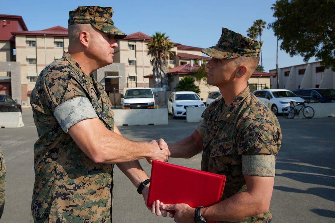 U.S. Marine Corps Col. Caleb Hyatt, left, commanding officer of the 11th Marine Expeditionary Unit, I Marine Expeditionary Force, presents the Navy and Marine Corps Commendation Medal to Maj. Richard Larger, information operations officer assigned to the 11th MEU, at Marine Corps Base Camp Pendleton, California, July 17, 2025. The 11th MEU recognizes Marines who set the standard through sustained dedication to the mission. (U.S. Marine Corps photo by Lance Cpl. Aimee Jordan)