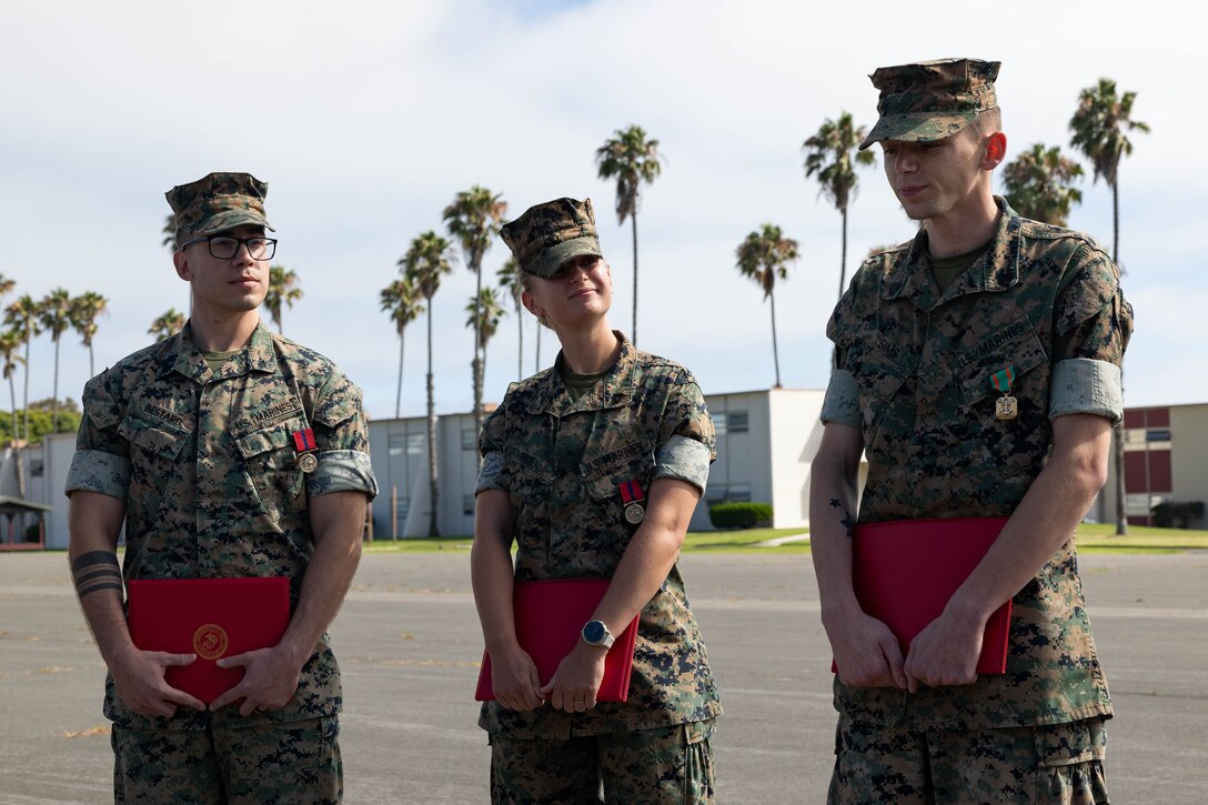 U.S. Marine Corps Cpl. Daniel Bestard, left, a data systems administrator, Sgt. Ellen Rick, middle, a ground electronics maintenance repair specialist, and Sgt. Austin Sims, a ground electronics transmissions systems maintainer, all with the 11th Marine Expeditionary Unit, I Marine Expeditionary Force, address the formation after an awards ceremony at Marine Corps Base Camp Pendleton, California, July 31, 2025. The 11th MEU regularly recognizes Marines who embody the standard through steady dedication to the mission. (U.S. Marine Corps photo by Lance Cpl. Luke Rodriguez)