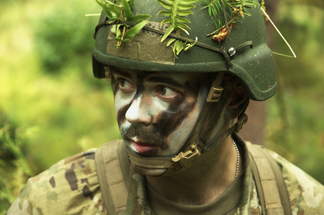 A close-up of a officer candidate in camouflage in a wooded area.