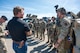A man in civilian attire speaks to uniformed personnel.