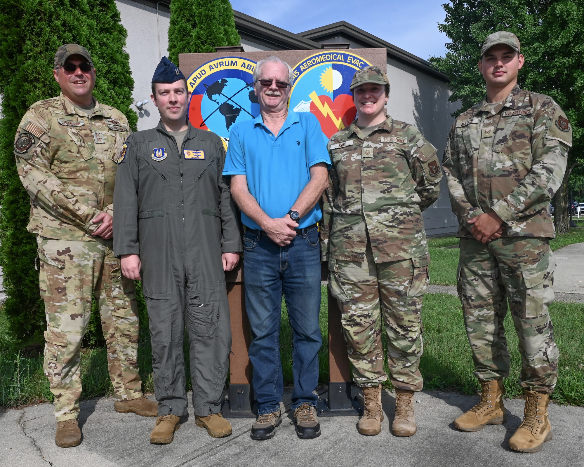 (left to right) U.S. Air Force Senior Master Sgt. Jerald Cremeens, Capt. Travis Egger, Steve Palsgrove, Master Sgt. Holly Knox and Staff Sgt. Patrick McClain, 445th Operations Support Squadron current operations section, pose in front of their squadron shield at Wright-Patterson Air Force Base, Ohio, July 21, 2025. McClain is a traditional reservist on orders while the other four work full time during the week. (U.S. Air Force photo by Amanda Dick)