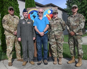 (left to right) U.S. Air Force Senior Master Sgt. Jerald Cremeens, Capt. Travis Egger, Steve Palsgrove, Master Sgt. Holly Knox and Staff Sgt. Patrick McClain, 445th Operations Support Squadron current operations section, pose in front of their squadron shield at Wright-Patterson Air Force Base, Ohio, July 21, 2025. McClain is a traditional reservist on orders while the other four work full time during the week. (U.S. Air Force photo by Amanda Dick)