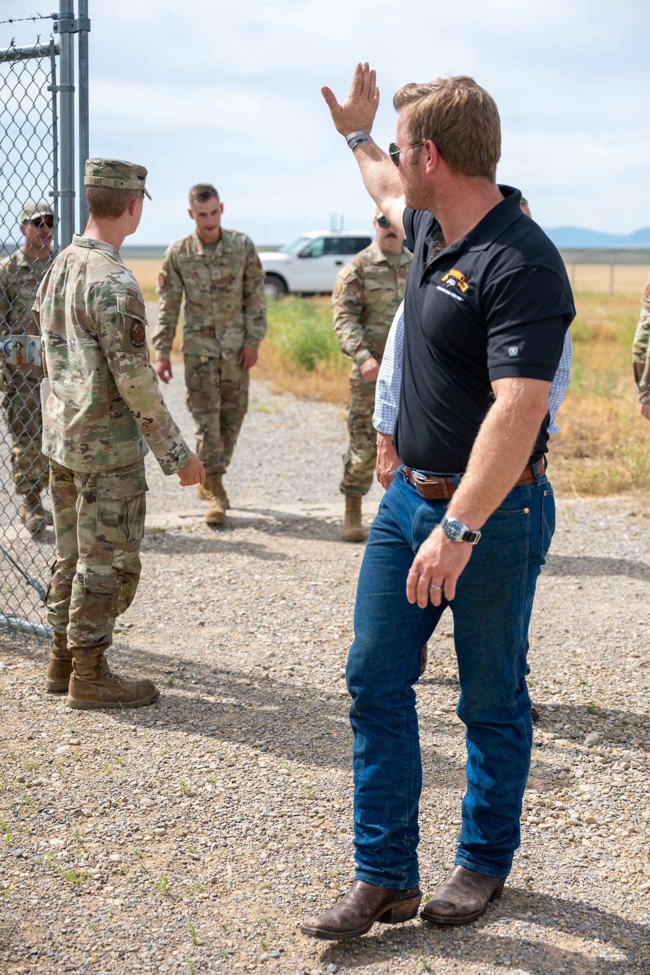 A man in civilian attire waves behind him.