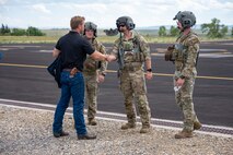 A man in civilian attire shakes hands with a man in uniform.