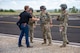 A man in civilian attire shakes hands with a man in uniform.