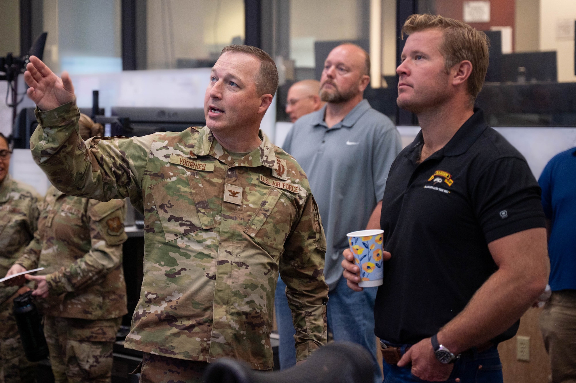 A man in uniform points something out to a man in civilian attire.
