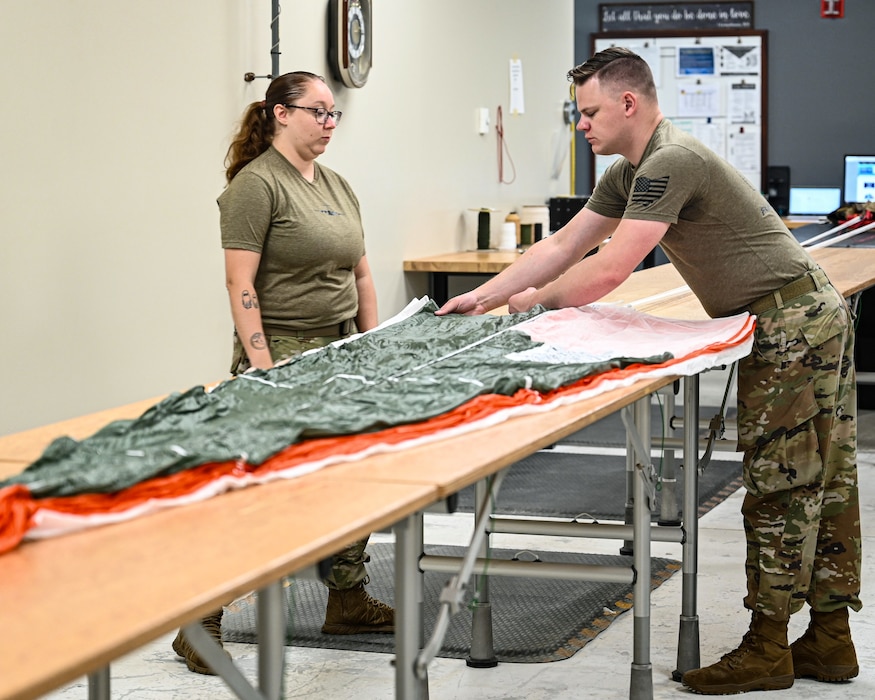 U.S. Air Force Staff Sgt. Gabrielle Saidak, left, 445th Operation Support Squadron Aircrew Flight Equipment air continuation instructor, trains Tech. Sgt. Andrew Emmons, 445th OSS AFE craftsman, on BA-30 parachutes at Wright-Patterson Air Force Base, Ohio, July 21, 2025. Emmons is learning the fundamentals on BA-30 inspection, fold, repair and re-pack. (U.S. Air Force photo by Staff Sgt. Johnathan Quiñones)